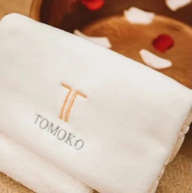 A white Tomoko towel embroidered with the gold T mark